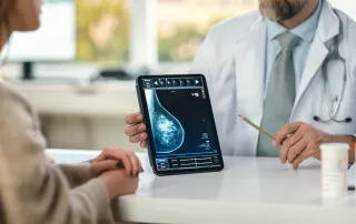professional doctor explaining breast ultrasound scan with technology to female patient